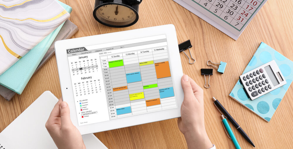 Woman using calendar app on tablet at table, closeup